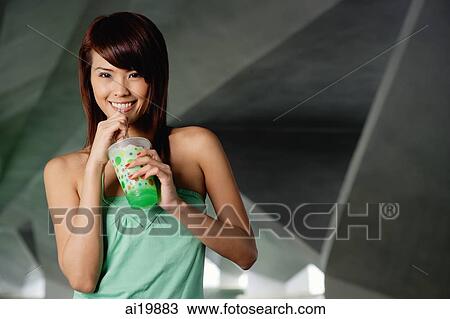 Stock Image - Woman in green top with green drink. Fotosearch