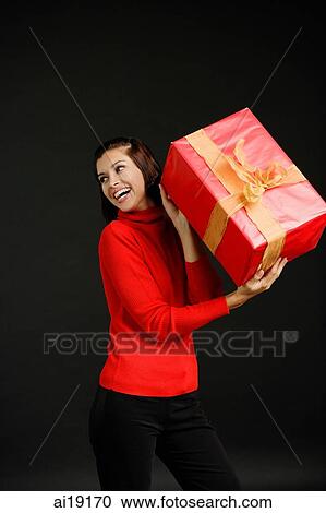 Woman in red turtleneck holding gift, looking away View Large Photo Image Stock Image - Woman in red turtleneck holding gift, looking away. Fotosearch