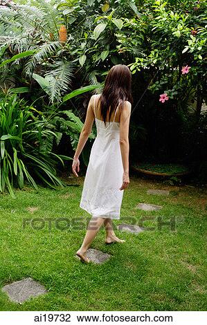 Woman in white dress walking in garden View Large Photo Image Stock Image - Woman in white dress walking in garden. Fotosearch