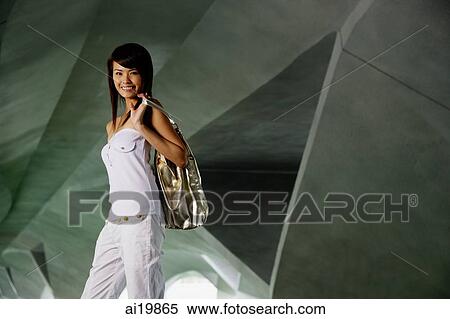 Stock Photography - Woman in white tube top, carrying bag over shoulder. Fotosearch