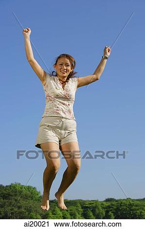 Woman jumping in mid air, smiling at camera View Large Photo Image Stock Image - Woman jumping in mid air, smiling at camera. Fotosearch