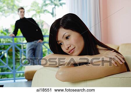 Woman leaning head on folded arms, looking away, man in the background View Large Photo Image Stock Image - Woman leaning head on folded arms, looking away, man in the background. Fotosearch