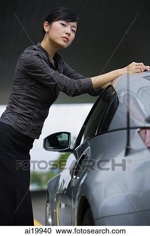 Woman leaning on car, looking at camera View Large Photo Image Stock Image - Woman leaning on car, looking at camera. Fotosearch