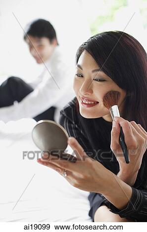 Woman looking at compact, applying make-up View Large Photo Image Stock Photo - Woman looking at compact, applying make-up. Fotosearch