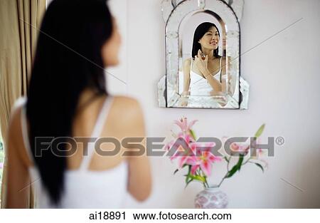 Woman looking into mirror, spraying perfume on neck View Large Photo Image Stock Image - Woman looking into mirror, spraying perfume on neck. Fotosearch