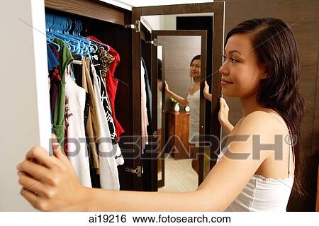 Woman looking into wardrobe full of clothes View Large Photo Image Stock Photograph - Woman looking into wardrobe full of clothes. Fotosearch