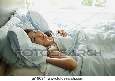 Woman lying in bed, smiling at camera View Large Photo Image Picture - Woman lying in bed, smiling at camera. Fotosearch