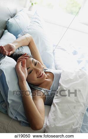 Woman lying in bed, smiling View Large Photo Image Stock Image - Woman lying in bed, smiling. Fotosearch