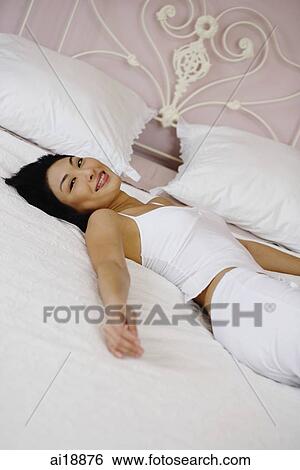 Woman lying on bed, looking at camera View Large Photo Image Stock Photograph - Woman lying on bed, looking at camera. Fotosearch