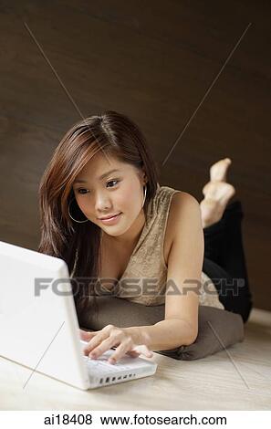 Woman lying on floor, using laptop View Large Photo Image Stock Photo - Woman lying on floor, using laptop. Fotosearch