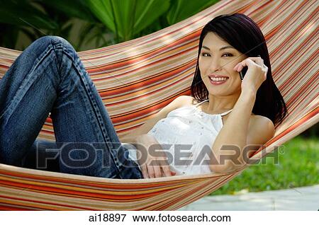 Woman lying on hammock, using mobile phone View Large Photo Image Stock Photo - Woman lying on hammock, using mobile phone. Fotosearch