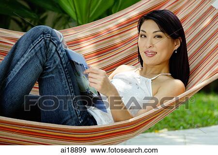 Stock Photo - Woman lying on hammock with magazine. Fotosearch