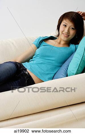 Woman lying on sofa, looking at camera View Large Photo Image Stock Image - Woman lying on sofa, looking at camera. Fotosearch