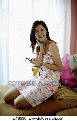 Woman on bed, listening to MP3 player, looking at camera View Large Photo Image Stock Photograph - Woman on bed, listening to MP3 player, looking at camera. Fotosearch