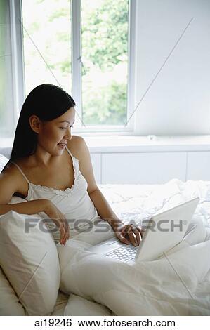 Woman on bed, using laptop View Large Photo Image Stock Photograph - Woman on bed, using laptop. Fotosearch