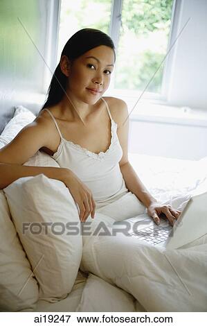 Woman on bed with laptop, looking at camera View Large Photo Image Stock Photo - Woman on bed with laptop, looking at camera. Fotosearch
