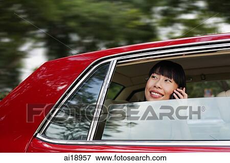 Woman sitting in car, using mobile phone, smiling View Large Photo Image Stock Photo - Woman sitting in car, using mobile phone, smiling. Fotosearch