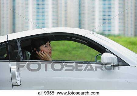 Woman sitting in silver sports car, using mobile phone View Large Photo Image Stock Photography - Woman sitting in silver sports car, using mobile phone. Fotosearch