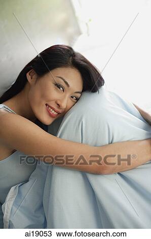 Woman sitting on bed, hugging knees, smiling at camera View Large Photo Image Stock Image - Woman sitting on bed, hugging knees, smiling at camera. Fotosearch