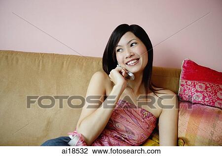 Woman sitting on sofa, using mobile phone View Large Photo Image Stock Image - Woman sitting on sofa, using mobile phone. Fotosearch