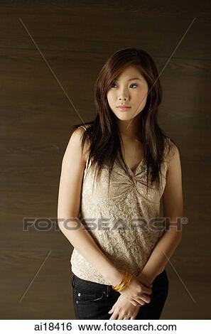 Woman standing against dark wall, looking away View Large Photo Image Stock Photograph - Woman standing against dark wall, looking away. Fotosearch