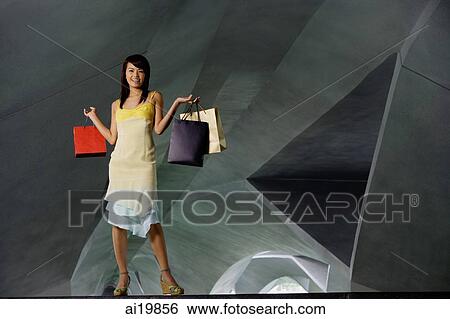 Stock Photograph - Woman standing in tunnel, carrying shopping bags. Fotosearch