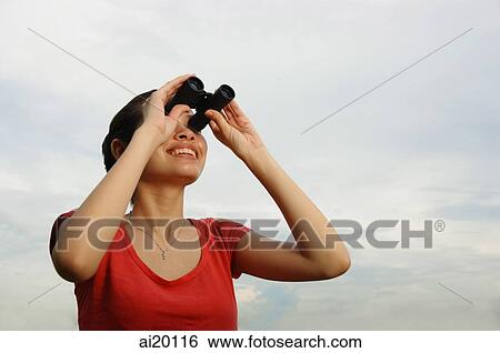 Stock Photograph - Woman using binoculars, smiling. Fotosearch