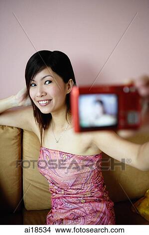 Woman using camera to take photo of herself View Large Photo Image Picture - Woman using camera to take photo of herself. Fotosearch