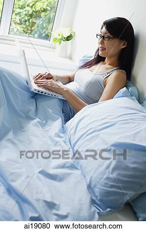 Woman using laptop in bedroom View Large Photo Image Stock Image - Woman using laptop in bedroom. Fotosearch