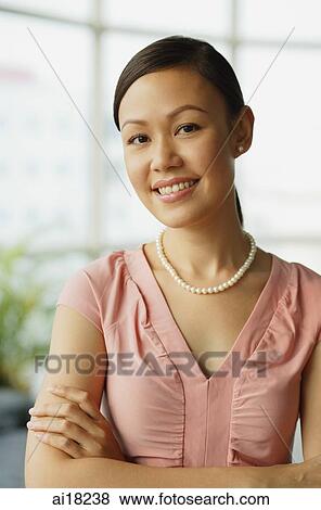 Woman with arms crossed, wearing pearl necklace, smiling at camera View Large Photo Image Stock Photo - Woman with arms crossed, wearing pearl necklace, smiling at camera. Fotosearch