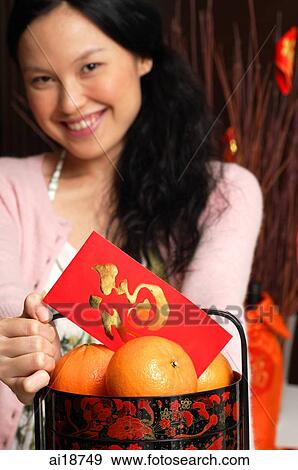 Woman with basket of oranges and red packet, smiling View Large Photo Image Stock Photo - Woman with basket of oranges and red packet, smiling. Fotosearch