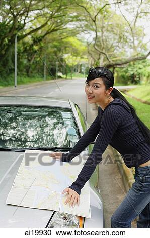 Woman with map spread out on hood of car, looking at camera View Large Photo Image Stock Image - Woman with map spread out on hood of car, looking at camera. Fotosearch