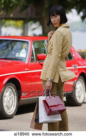 Woman with shopping bags, turning to look at camera, car in the background View Large Photo Image Stock Photography - Woman with shopping bags, turning to look at camera, car in the background. Fotosearch