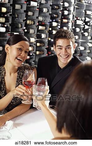 Young adults in restaurant, holding wine glasses, toasting View Large Photo Image Stock Image - Young adults in restaurant, holding wine glasses, toasting. Fotosearch