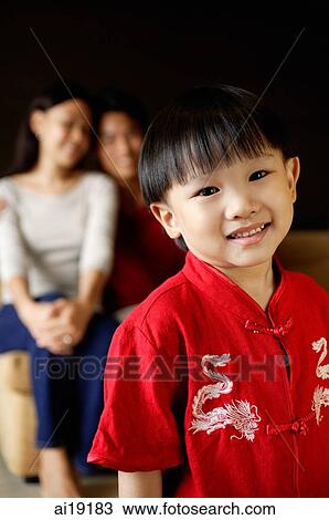 Young boy smiling at camera, parents in background View Large Photo Image Stock Image - Young boy smiling at camera, parents in background. Fotosearch