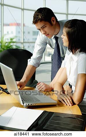 Young executives looking at laptop in office View Large Photo Image Stock Image - Young executives looking at laptop in office. Fotosearch