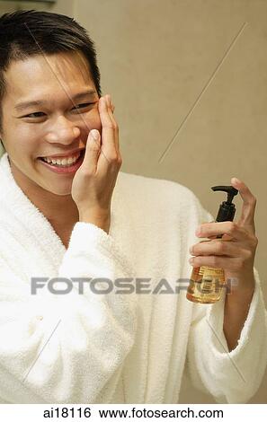 Young man applying lotion View Large Photo Image Stock Photograph - Young man applying lotion. Fotosearch