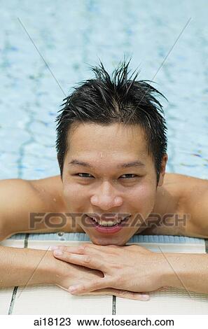Young man at edge of swimming pool, smiling at camera View Large Photo Image Stock Image - Young man at edge of swimming pool, smiling at camera. Fotosearch