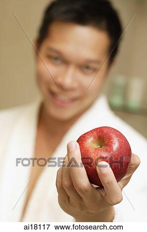 Stock Photo - Young man holding apple. Fotosearch