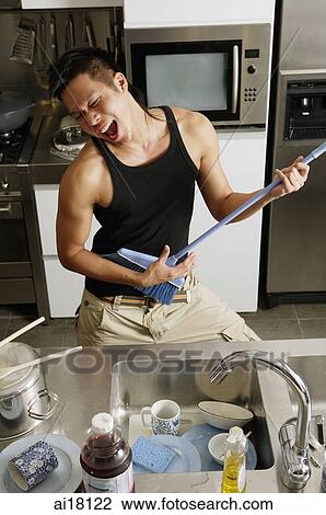 Young man in kitchen, holding broom like a guitar, singing View Large Photo Image Stock Image - Young man in kitchen, holding broom like a guitar, singing. Fotosearch