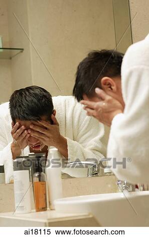 Young man washing face in bathroom View Large Photo Image Stock Photography - Young man washing face in bathroom. Fotosearch