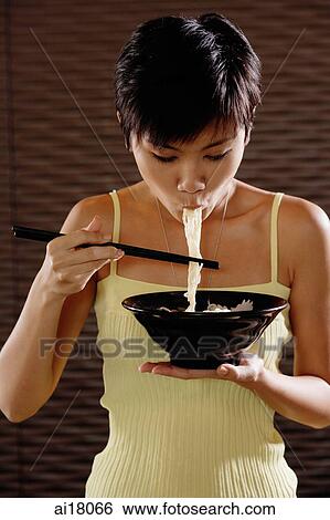 Young woman eating a bowl of noodles View Large Photo Image Stock Photograph - Young woman eating a bowl of noodles. Fotosearch