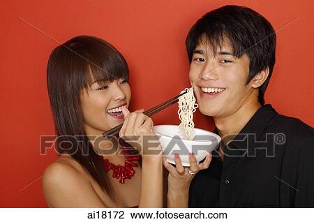 Stock Image - Young woman feeding man with noodles. Fotosearch