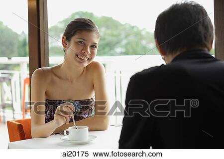 Young woman having coffee in restaurant, smiling at camera, man in the foreground View Large Photo Image Stock Photography - Young woman having coffee in restaurant, smiling at camera, man in the foreground. Fotosearch
