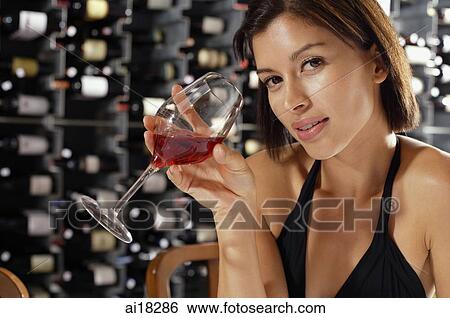 Young woman holding wine glass, looking at camera View Large Photo Image Stock Photograph - Young woman holding wine glass, looking at camera. Fotosearch