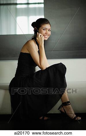 Young woman in black dress, using mobile phone View Large Photo Image Stock Image - Young woman in black dress, using mobile phone. Fotosearch