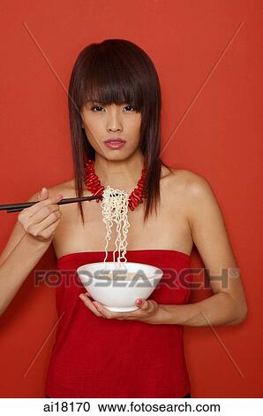Young woman in red, holding bowl of noodles, looking at camera View Large Photo Image Stock Image - Young woman in red, holding bowl of noodles, looking at camera. Fotosearch
