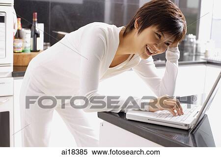 Young woman leaning on kitchen counter, using laptop View Large Photo Image Stock Photography - Young woman leaning on kitchen counter, using laptop. Fotosearch