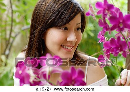 Stock Photo - Young woman looking at orchids. Fotosearch