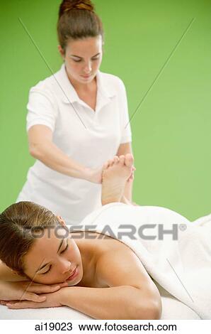 Stock Image - Young woman lying on massage table, being massaged. Fotosearch